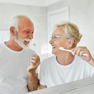 Senior couple smiling while brushing their teeth