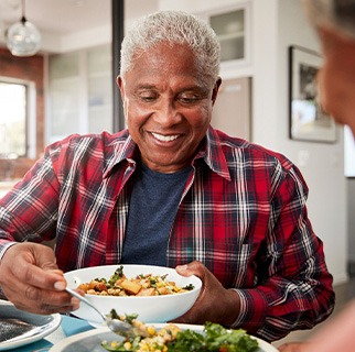 Senior man filling plate at table