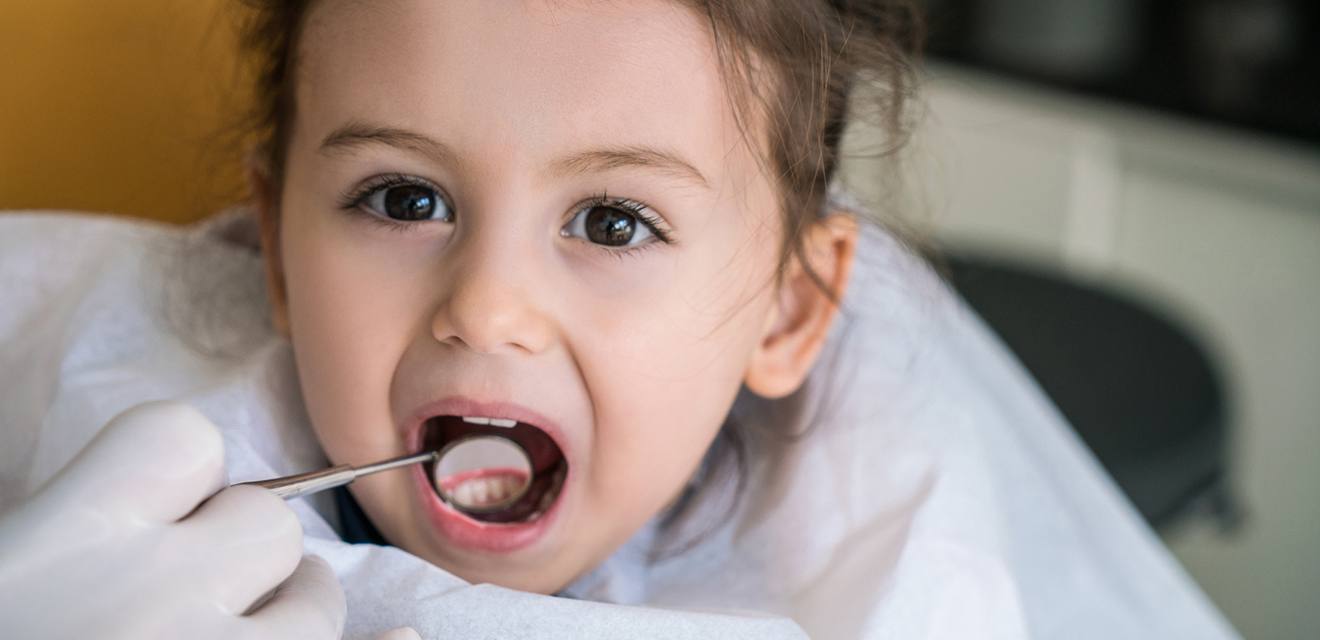 young girl with mouth open and dental mirrror in it