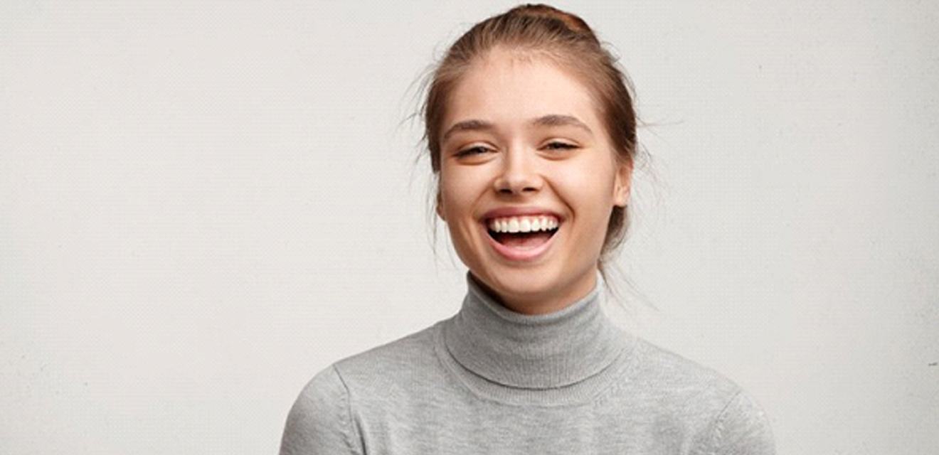 woman in a gray turtleneck sweater laughing