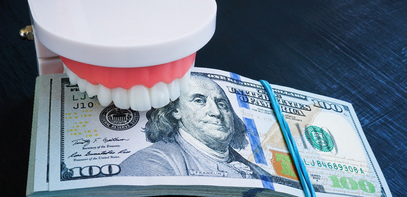 a plastic model of a mouth biting down on a stack of money