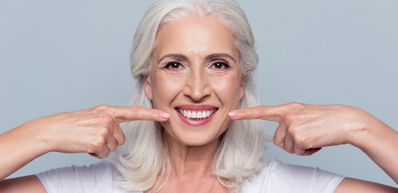 woman pointing to dentures with both hands