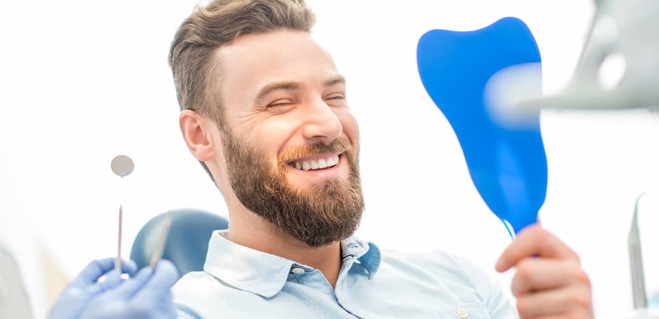 Young man admiring his new dental implants in Denver