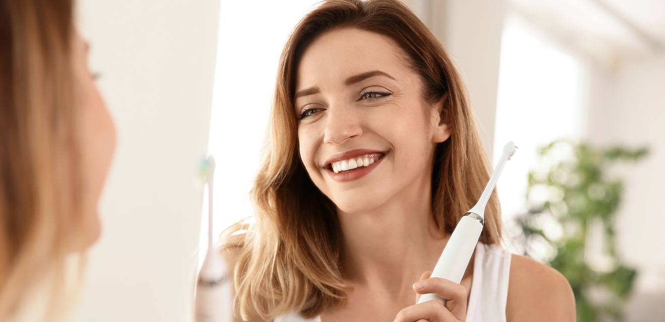 woman smiling holding onto toothbrush