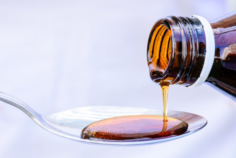 an image of a bottle of cough syrup being poured onto a spoon