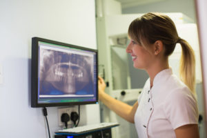Female dentist looking at dental x-ray on the screen