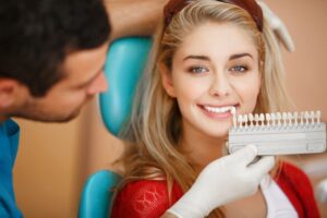 Dentist holding shade guide next to patient's teeth