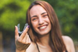 Woman holding clear Invisalign aligner. 